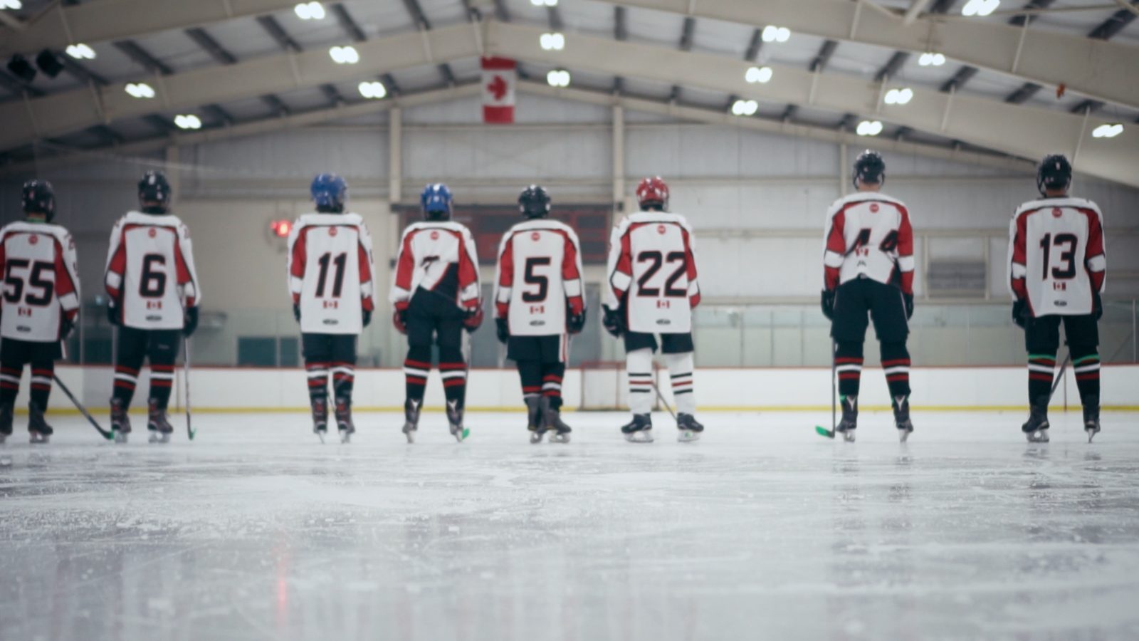 A youth hockey team lined up along the blue line, seen from behind