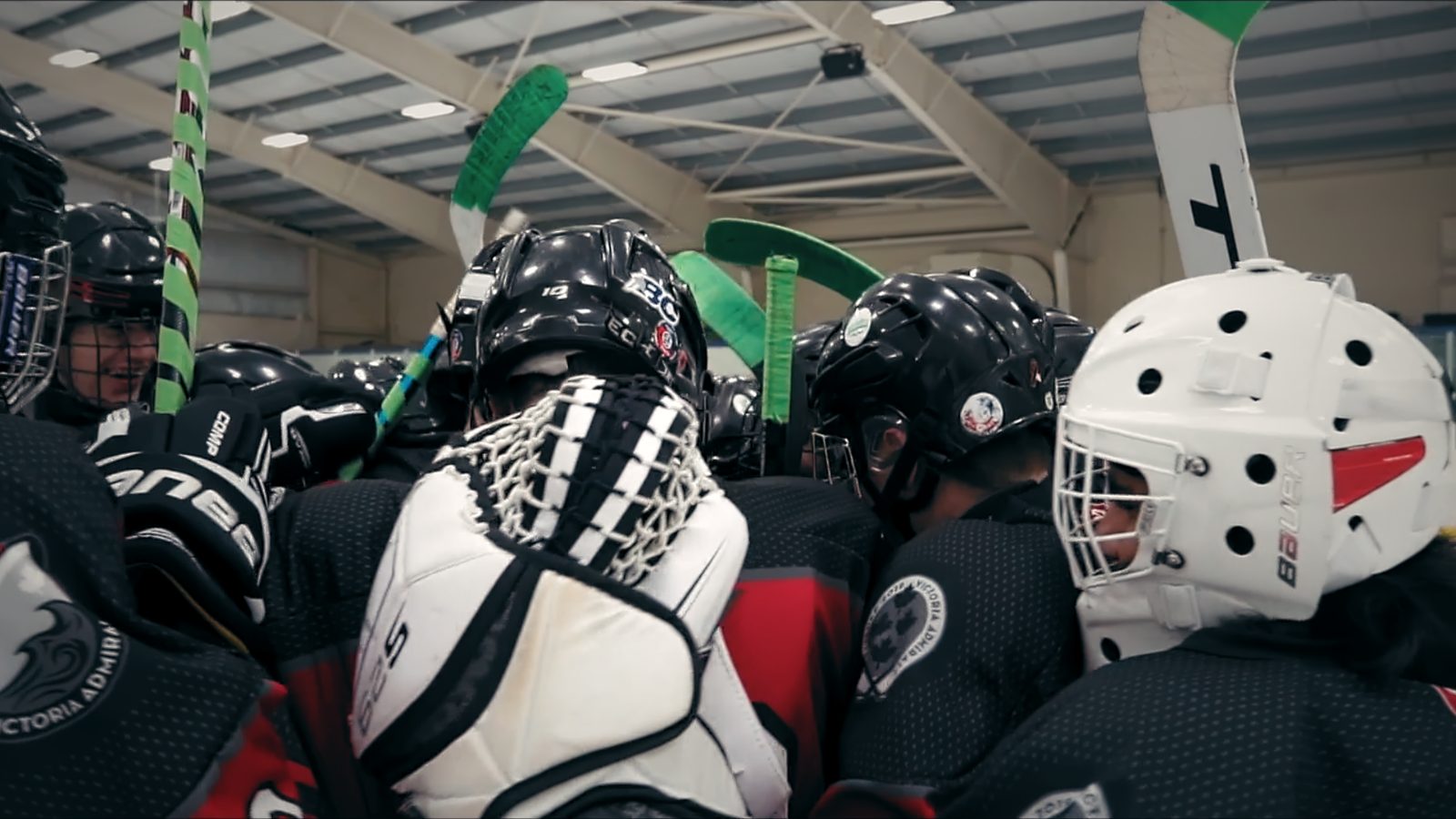 An on-ice team huddle with sticks raised together